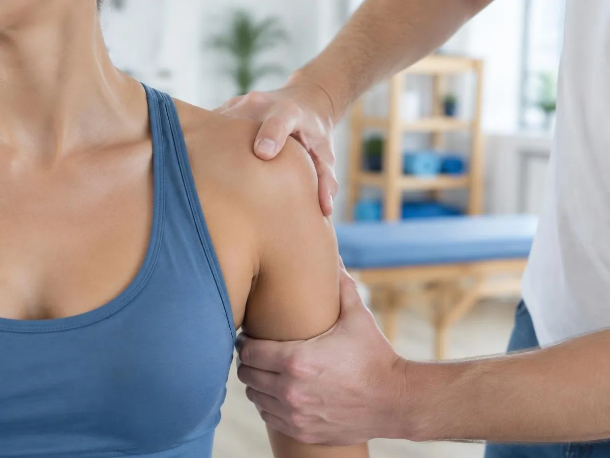 Mains mobilisant l'épaule d'une personne en débardeur de sport